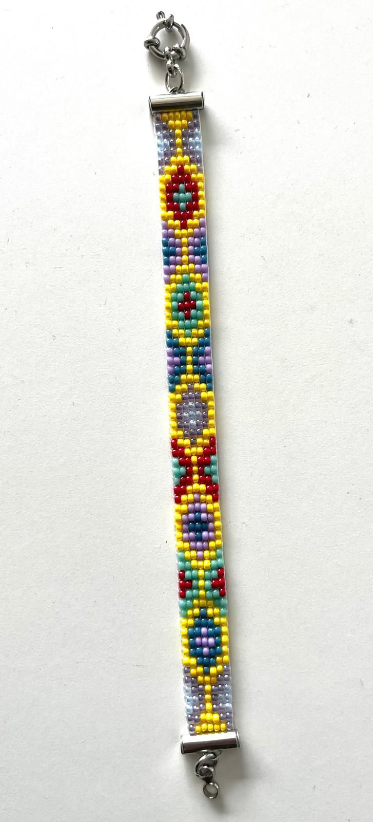 Kleurrijke kralenarmband met gele, blauwe, rode en witte patronen en een zilveren sluiting op een witte achtergrond.