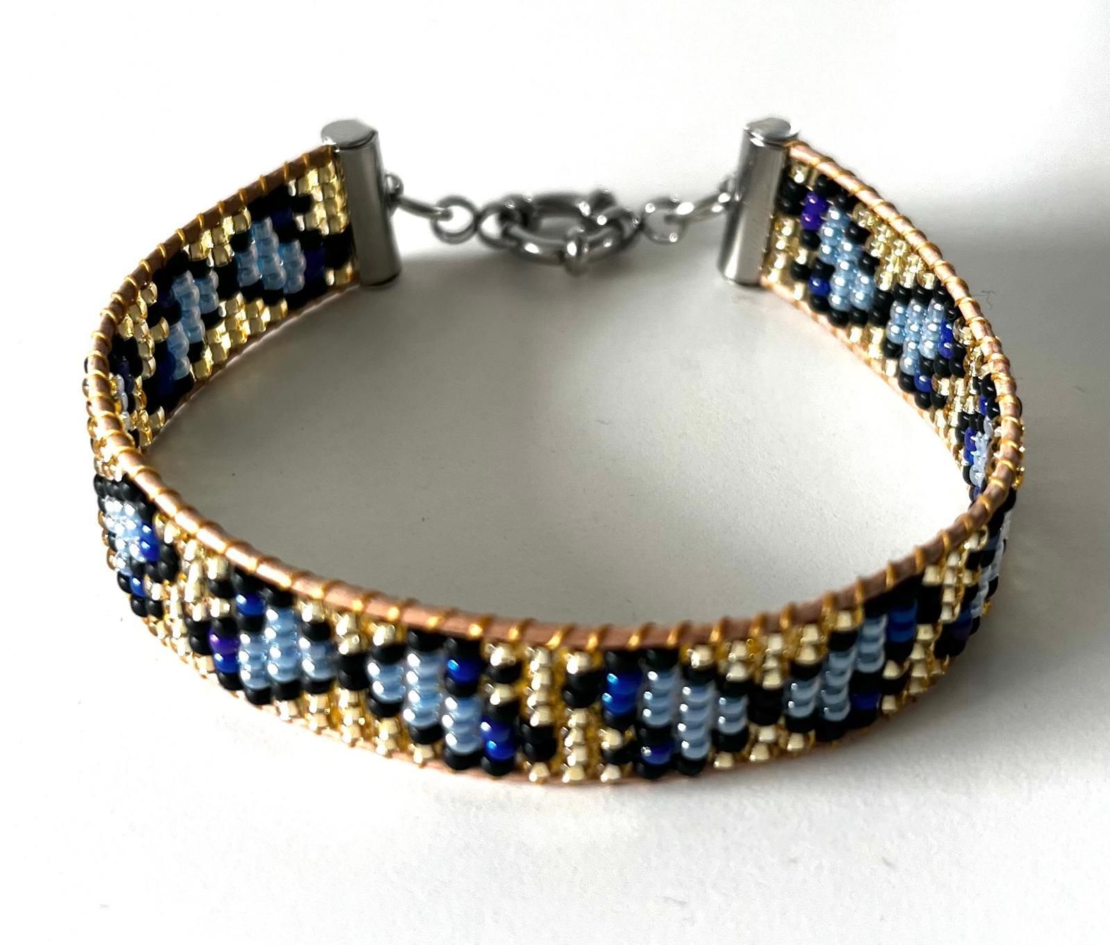Kralenarmband in blauw, goud en zwart met een sluiting.