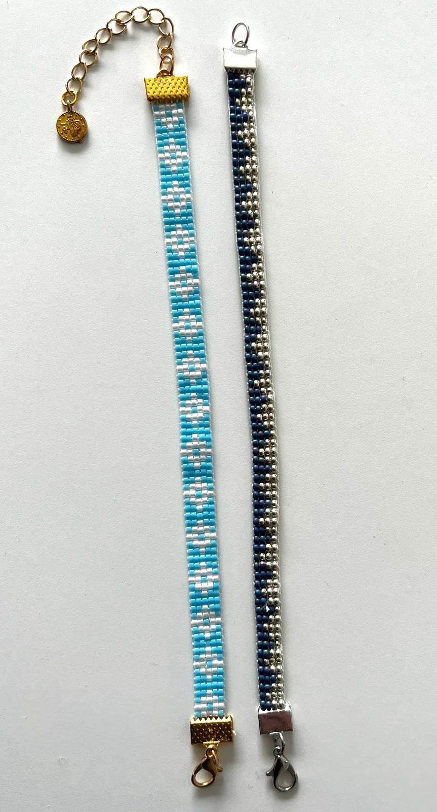 Blauw-witte kralenarmband met goudkleurige sluiting en verlengketting op een witte achtergrond.