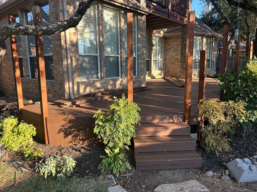 Wooden porch deck with steps, glass doors, and potted greenery in warm sunlight