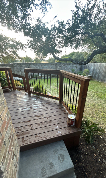 Wooden backyard deck with railing and steps beside a grassy yard and fence under a tree