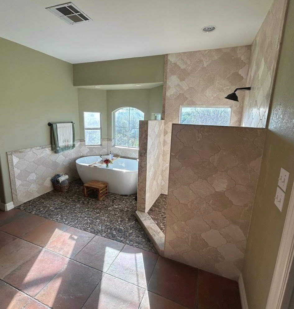 Spacious bathroom with bathtub, tiled shower, and patterned floor in soft beige tones