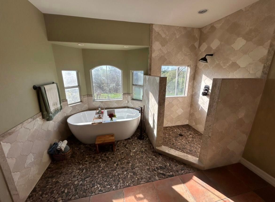 Bathroom with a freestanding tub, large walk-in shower, and beige tile walls and floor.