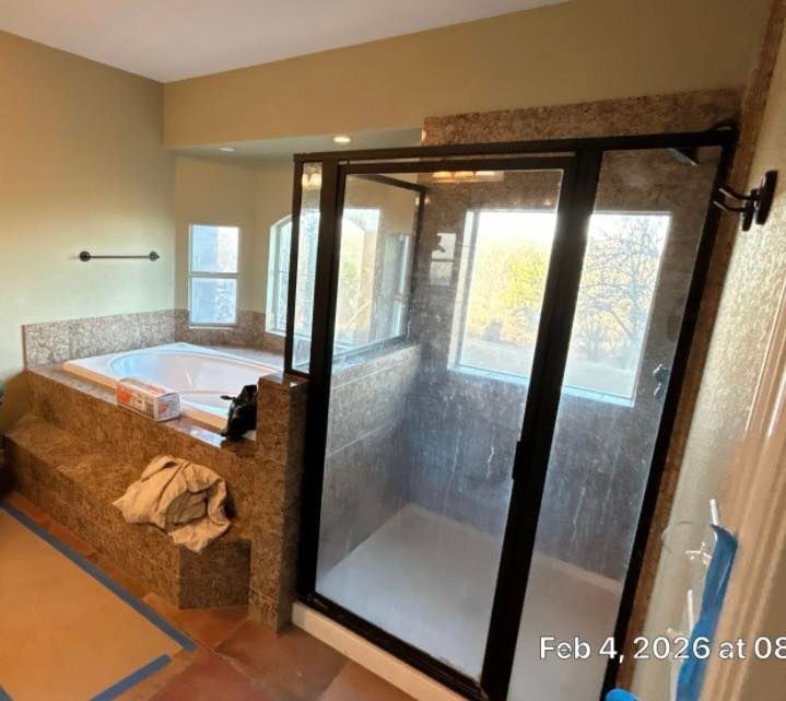 Bathroom with large glass shower enclosure and stone vanity beside a window