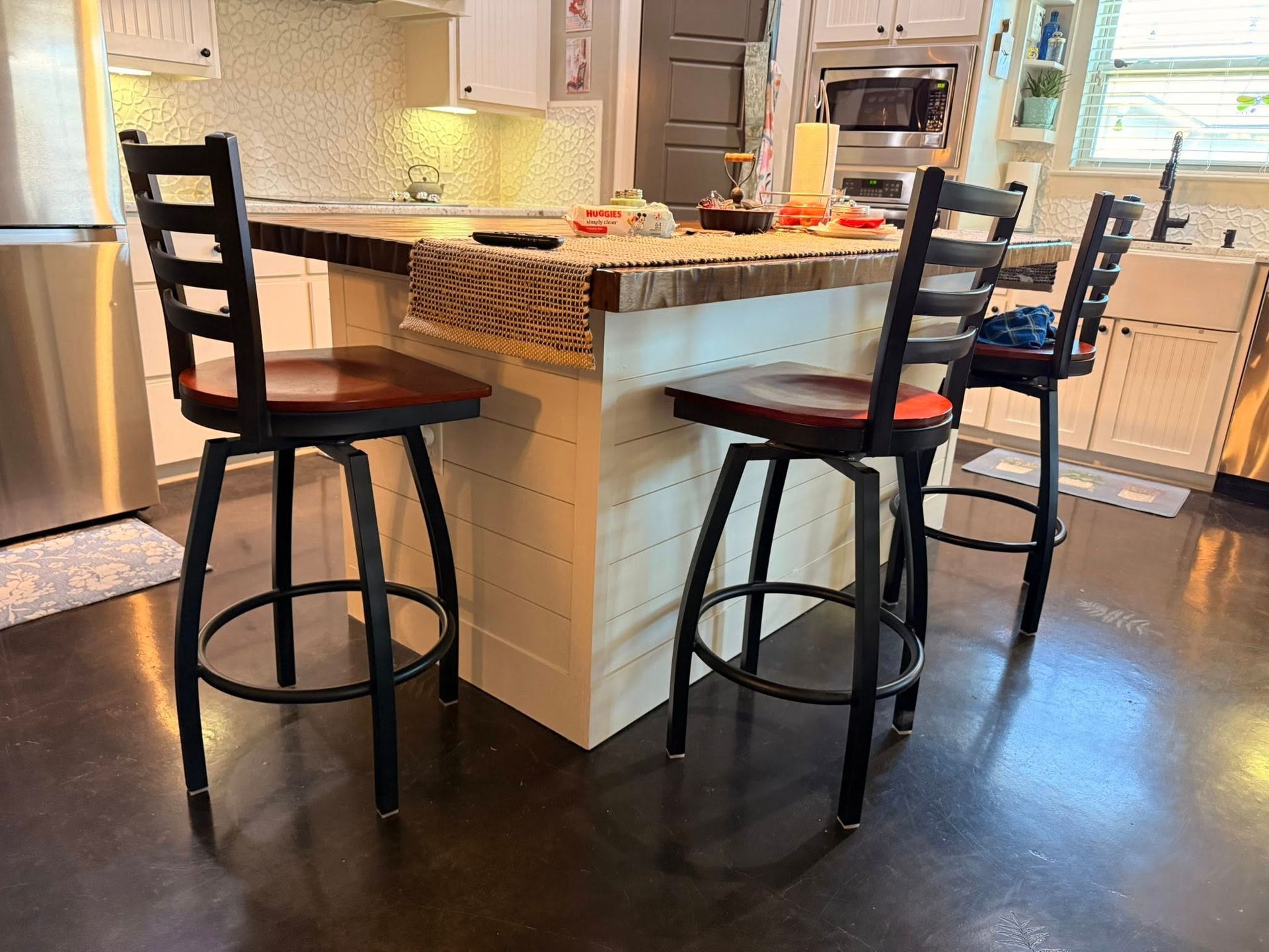 Kitchen island with two black barstools and pendant lights in a bright modern kitchen