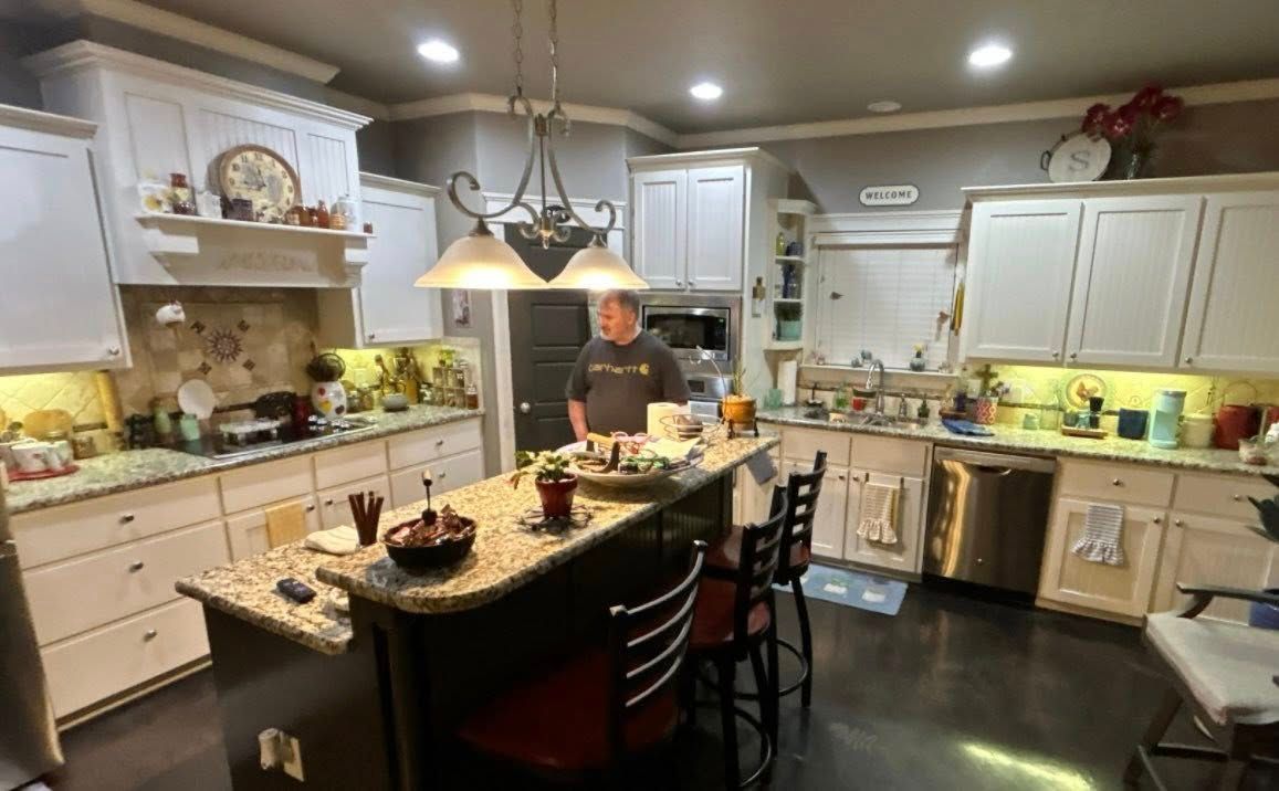 Modern kitchen with a person preparing food at a black island under pendant lights