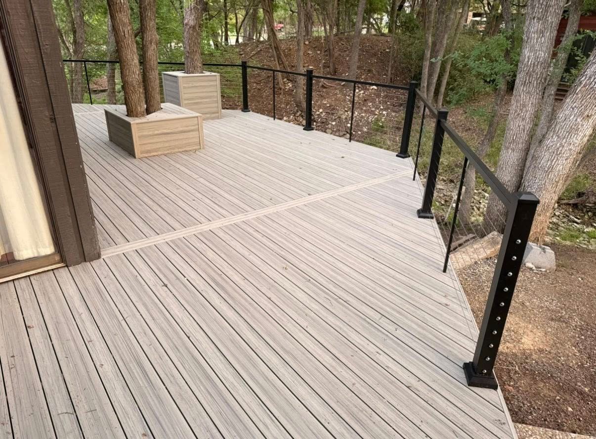 Wooden deck with black railing overlooking trees and a wooded yard