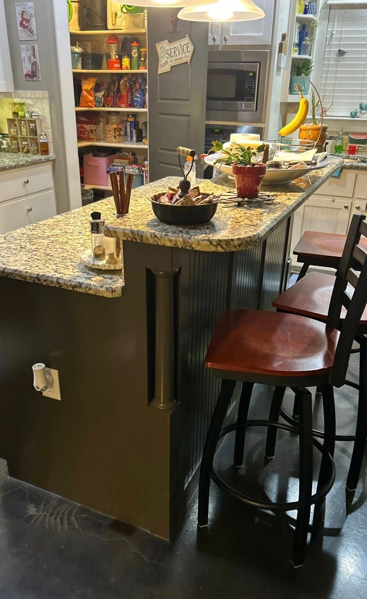 Kitchen island with granite countertop, bar stools, and a fruit bowl in a cozy home kitchen.