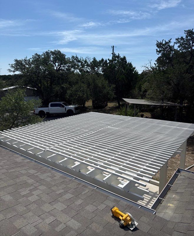 Rooftop solar panel array under construction, with a pickup truck and trees in the background.