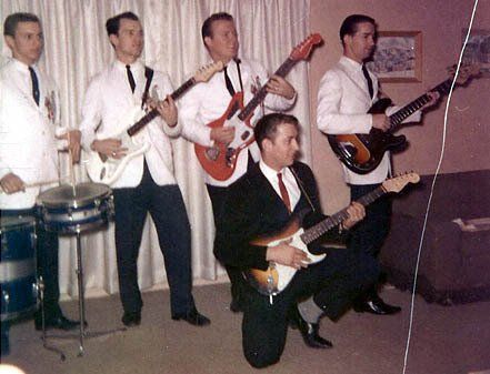 four men in white tops and black pants playing guitars