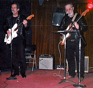 two men holding guitars on stage