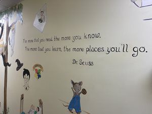 Wall with a Dr. Seuss quote, small cartoon characters, and a hanging paper decoration