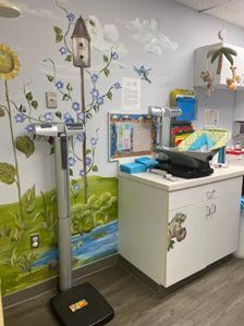 Children’s classroom scale with bird-themed wall mural and white cabinet in a clinical exam room