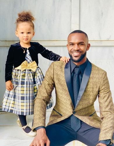 Adult and child posing together outdoors, both in dressy outfits and smiling at the camera