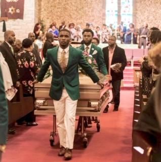 Mourners carrying a casket down a church aisle during a funeral service