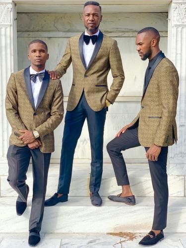 Three men in tan blazers and dress pants posing on steps outside a building.