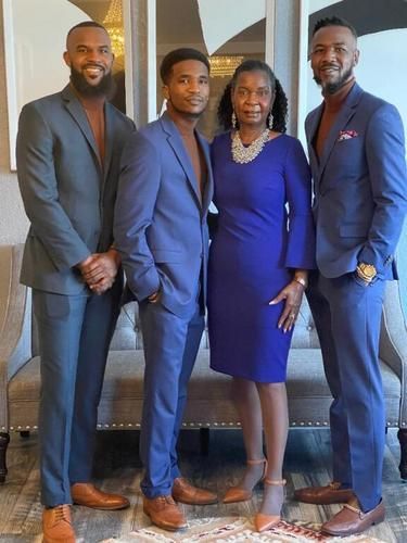Four people posing indoors in coordinated blue suits and dresses.