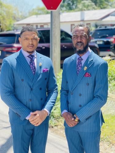 Two men in blue pinstripe suits standing outdoors on a sunny day