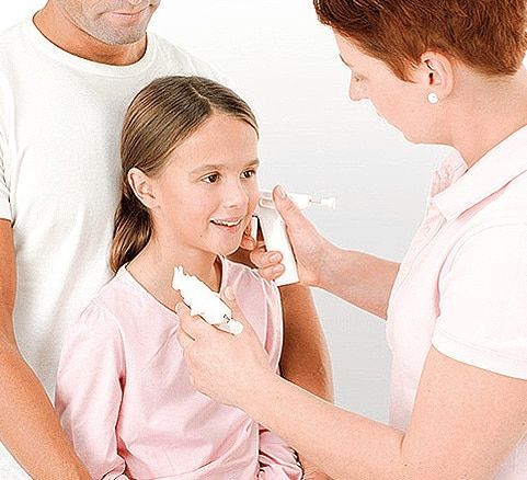 Healthcare worker applying medicine to a young girl's face while a man stands nearby