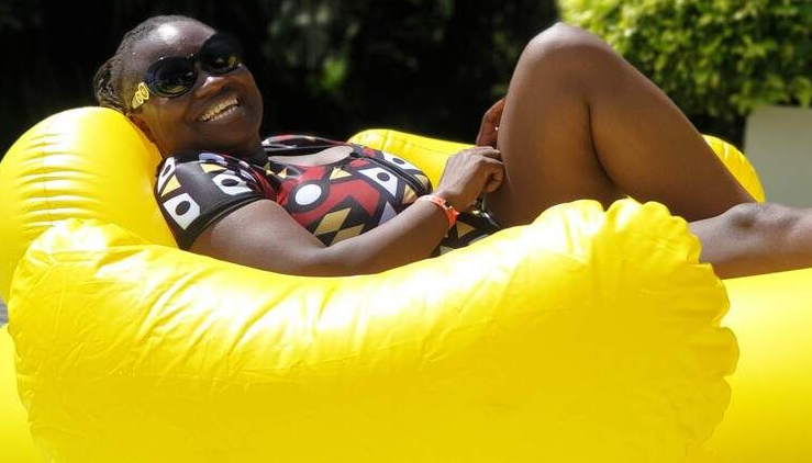 Person lounging on a bright yellow inflatable in a sunny outdoor pool area