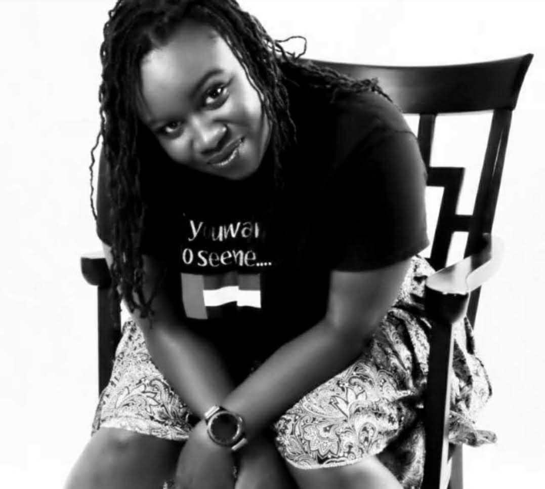 Person seated on a chair, leaning forward and smiling in a black-and-white portrait