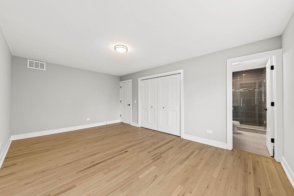 An empty room with hardwood floors and white walls.