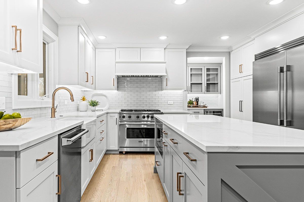 A kitchen with white cabinets , stainless steel appliances , and a large island.