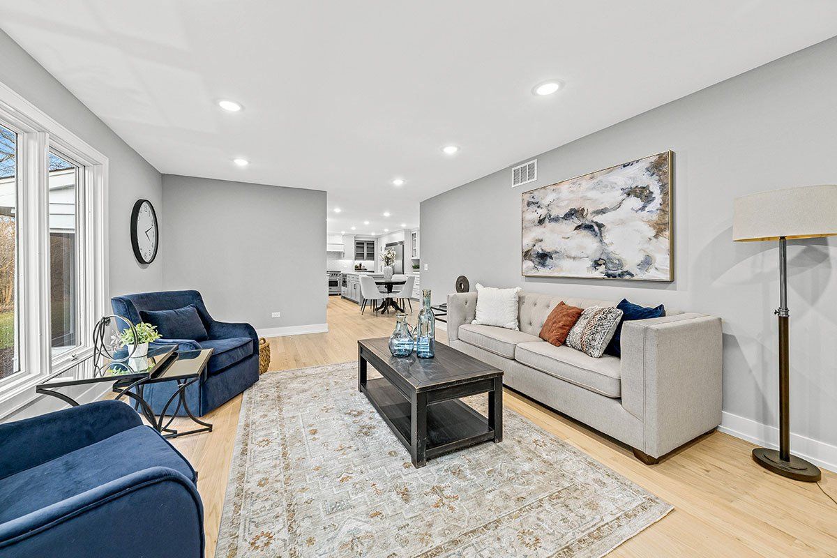 A living room with a couch , chair , coffee table and lamp.