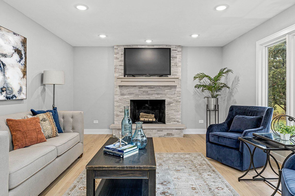 A living room with a couch , chair , coffee table , fireplace and television.