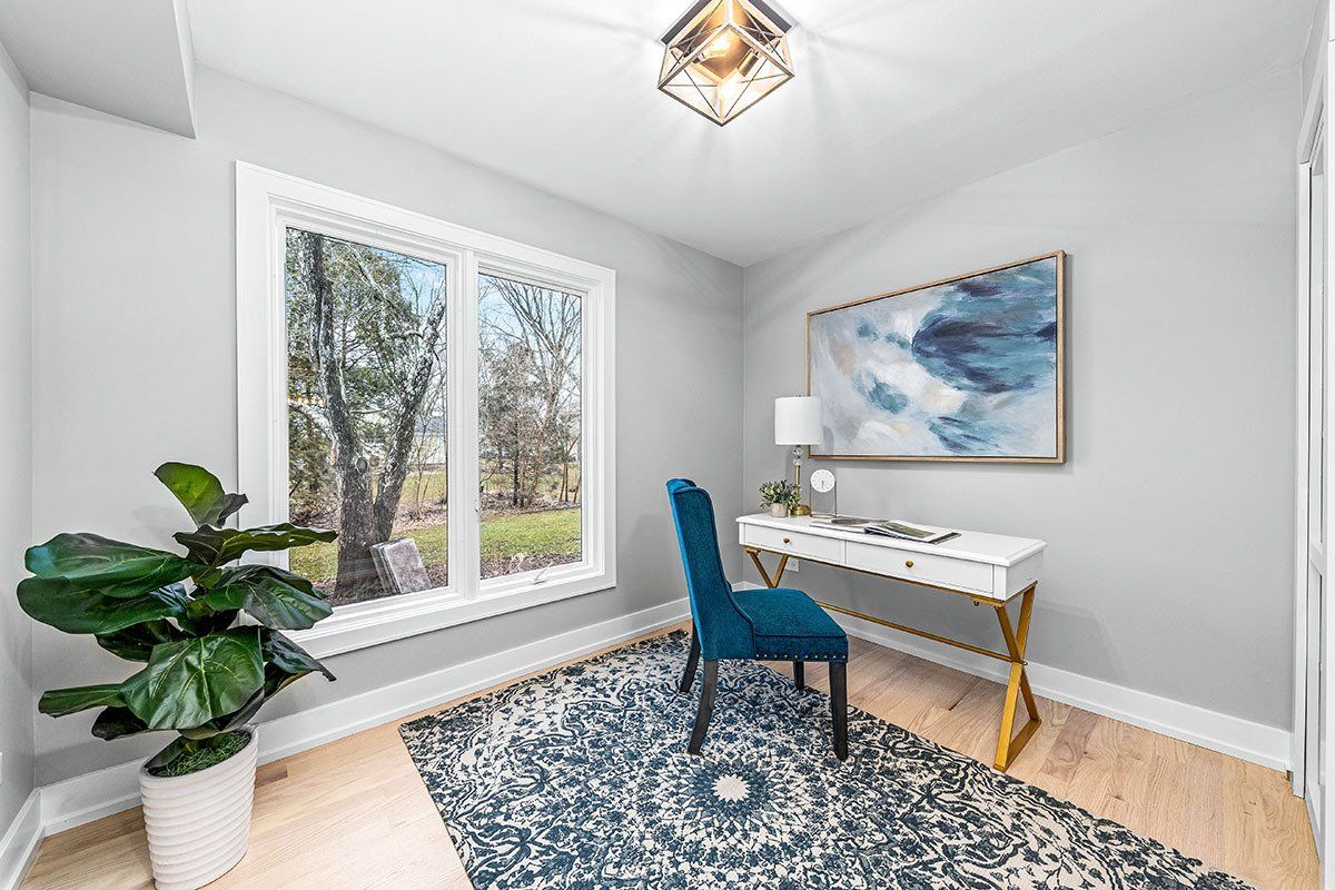 A home office with a desk , chair , rug and painting on the wall.