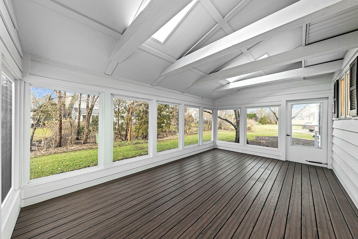 A large empty room with a wooden floor and lots of windows.