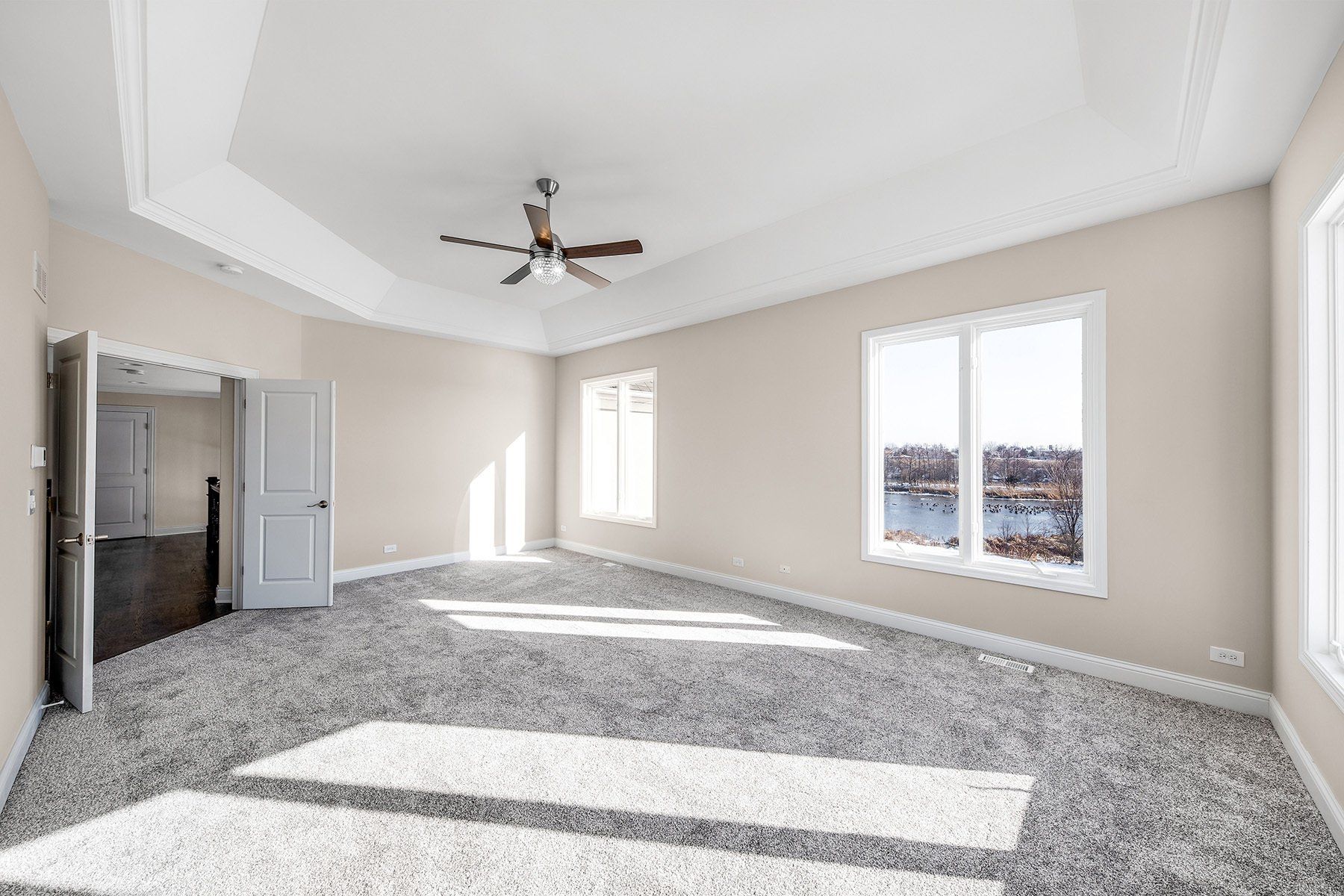A large empty room with a ceiling fan and a lot of windows.