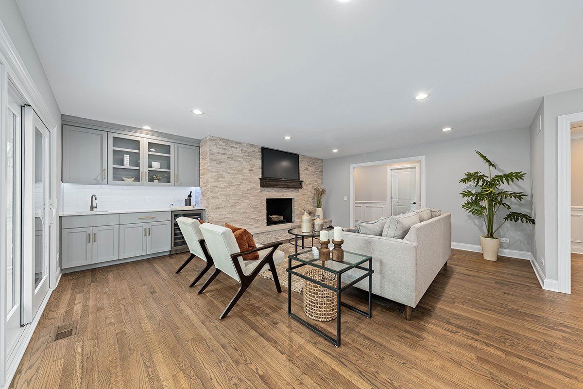 A living room with hardwood floors , a couch , chairs and a fireplace.