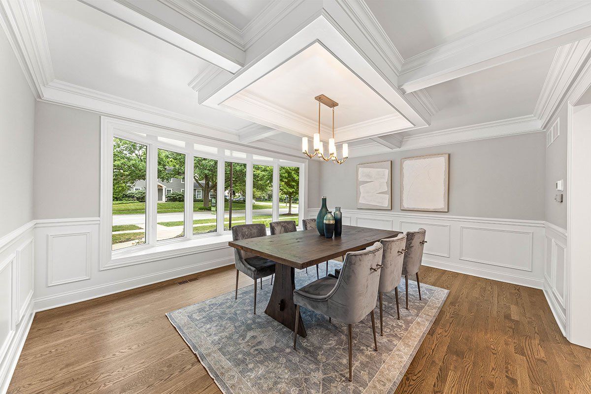 A dining room with a wooden table and chairs and a chandelier.