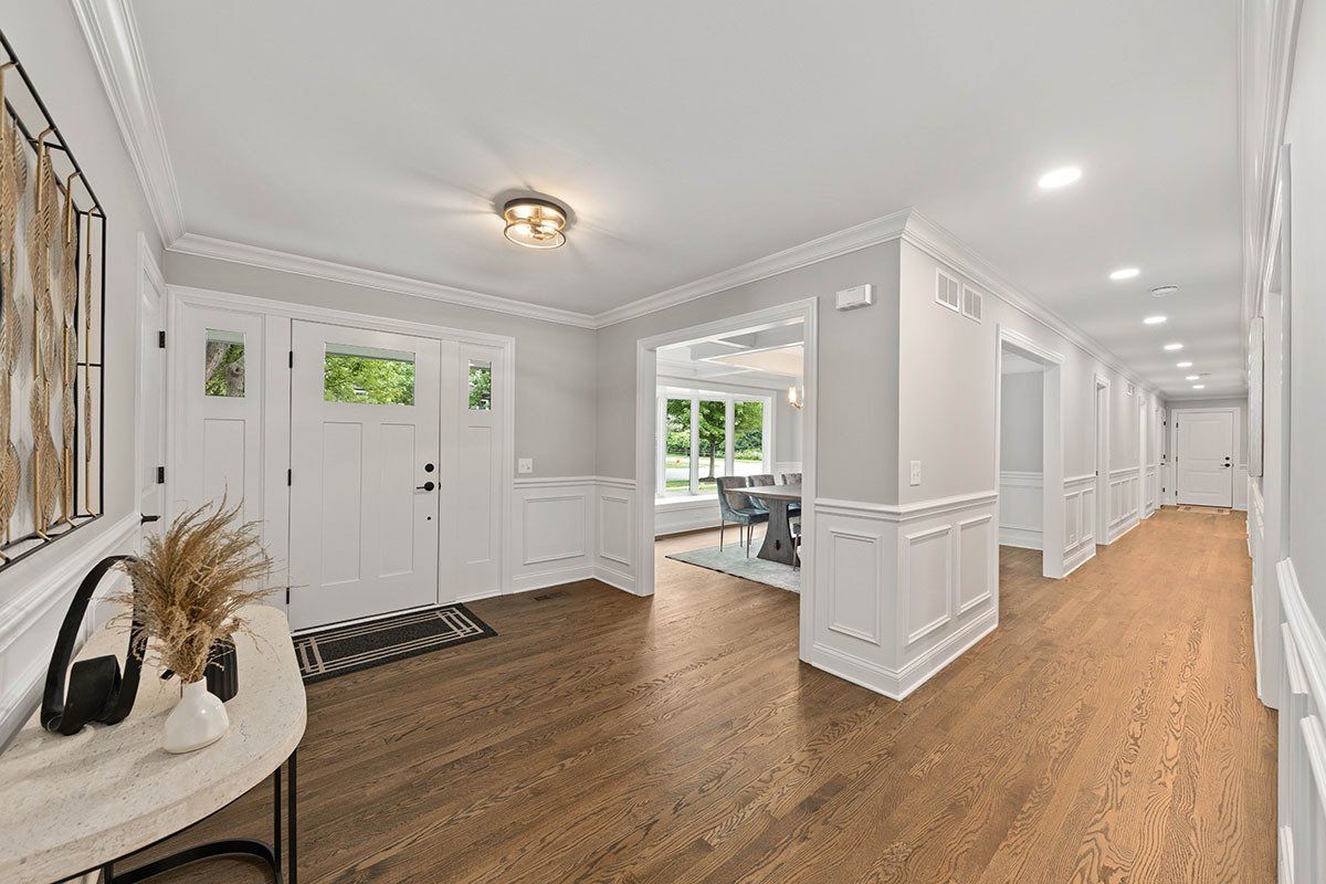 A long hallway in a house with hardwood floors and white trim.