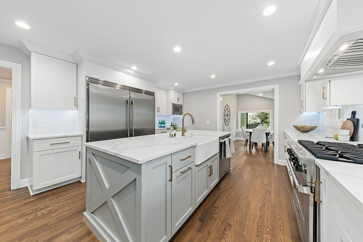 A kitchen with white cabinets and stainless steel appliances and a large island.
