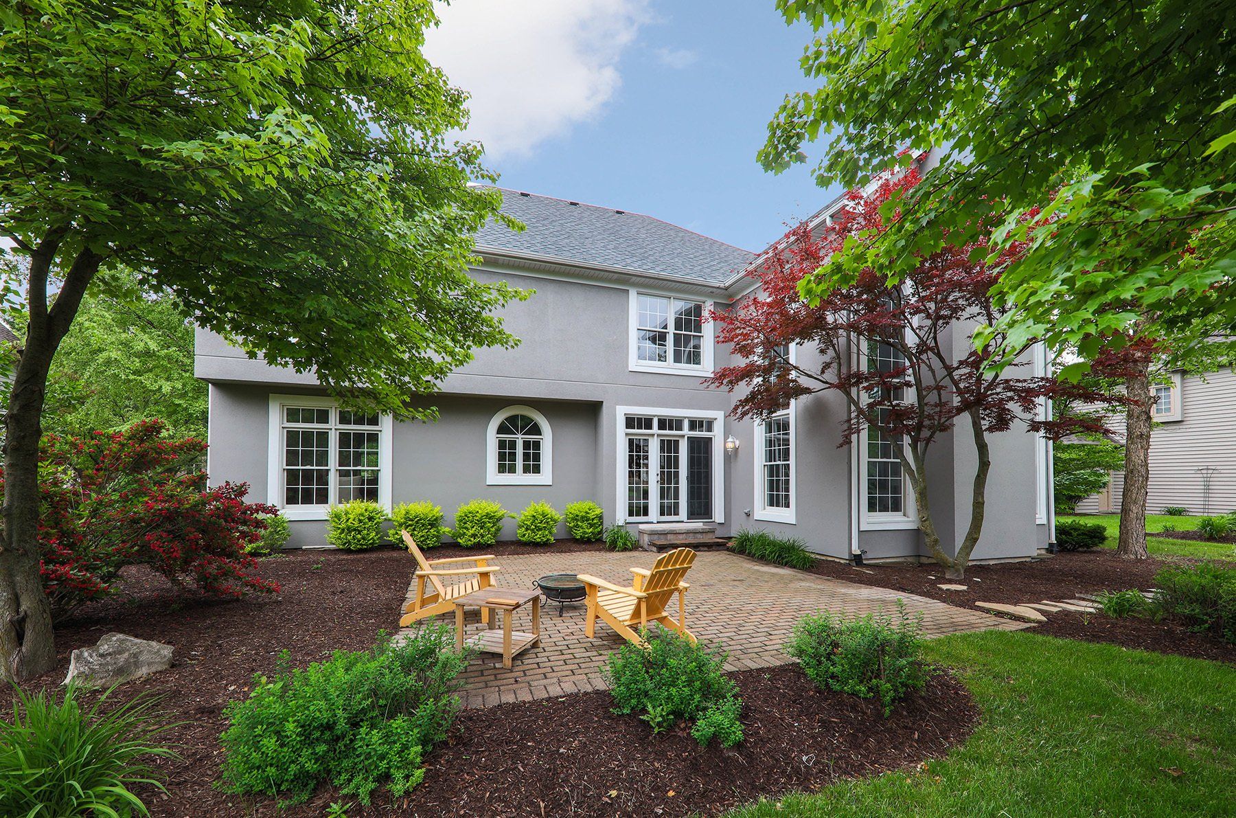 A large house with a patio and chairs in front of it.