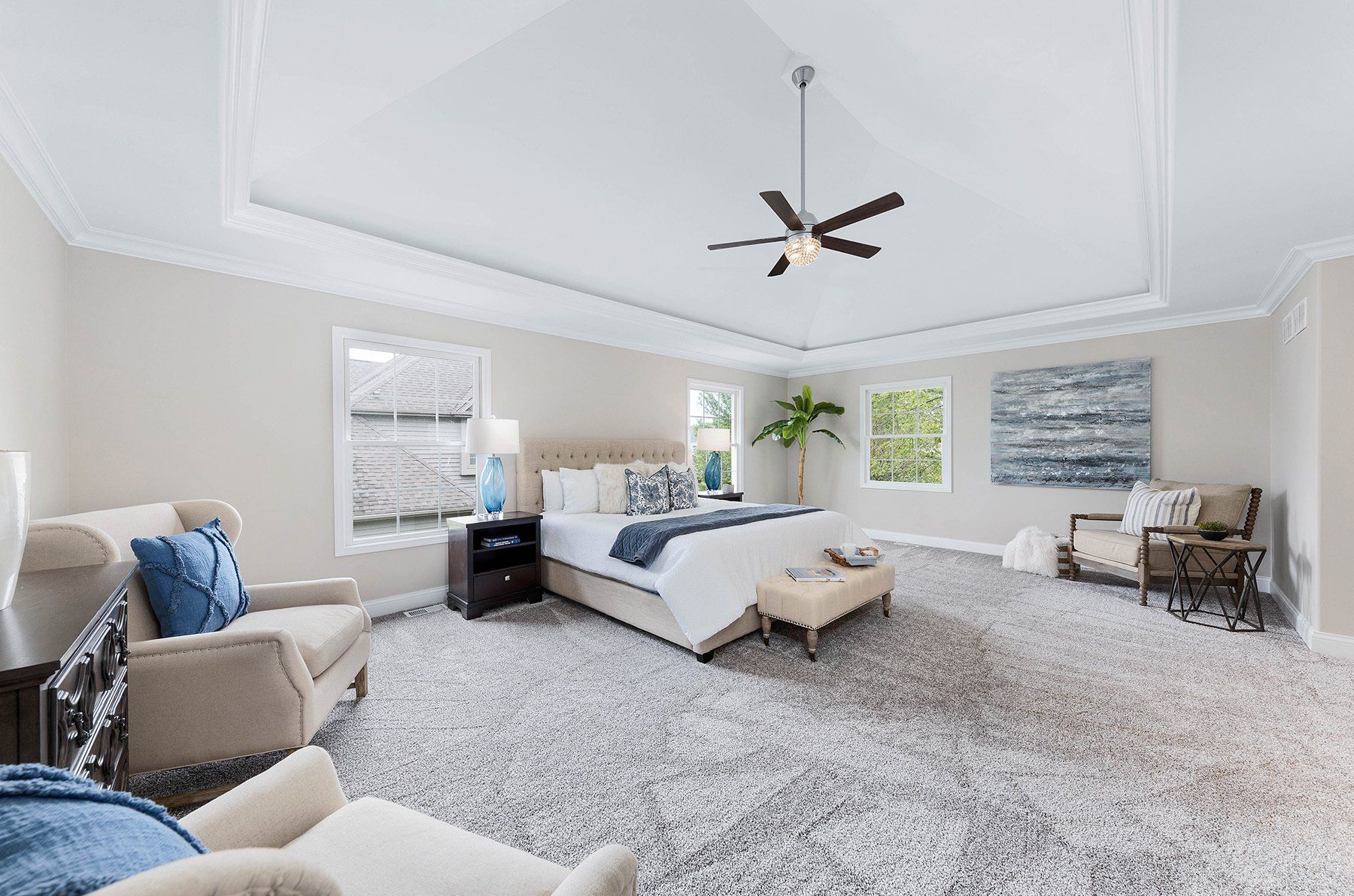A bedroom with a large bed , chairs , and a ceiling fan.