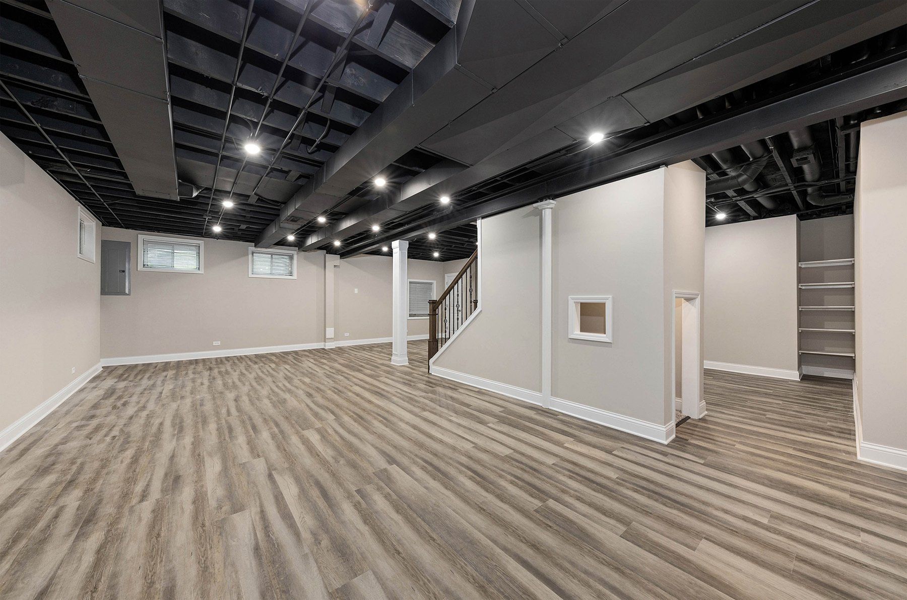An empty basement with hardwood floors and a staircase.