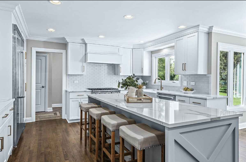 A kitchen with white cabinets and stools and a large island.