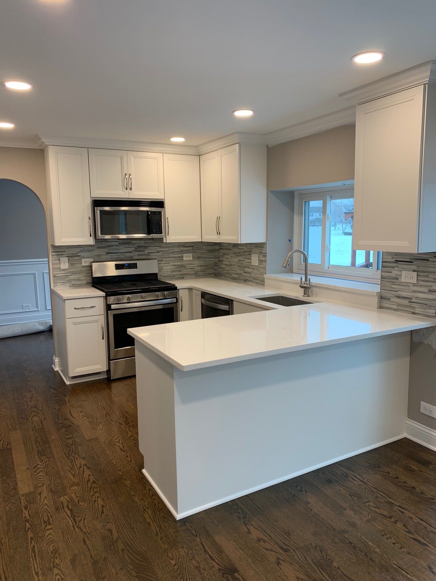 A kitchen with white cabinets , stainless steel appliances , and a large island.