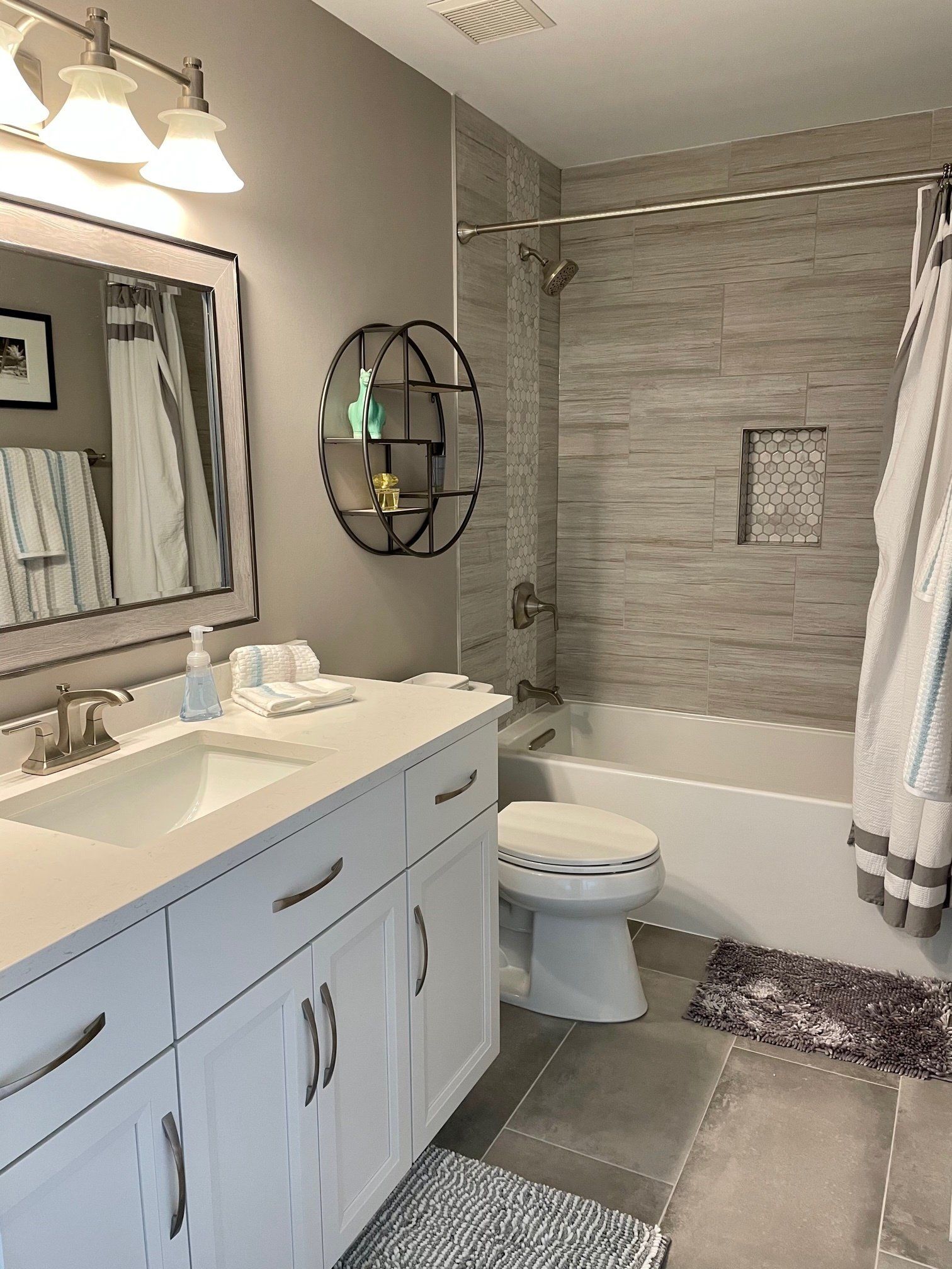 A bathroom with a sink , toilet , tub and mirror.