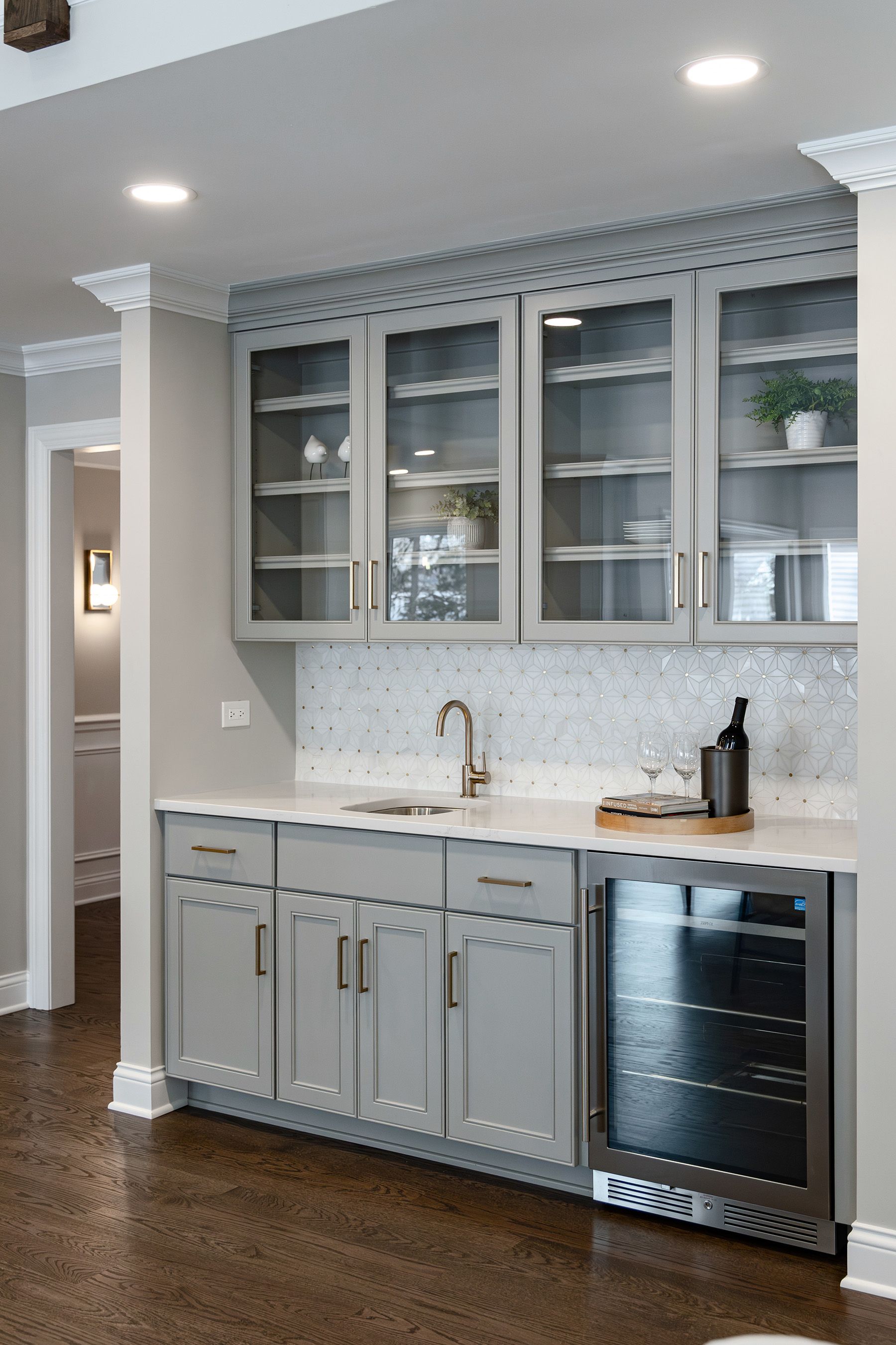A kitchen with gray cabinets and a stainless steel refrigerator