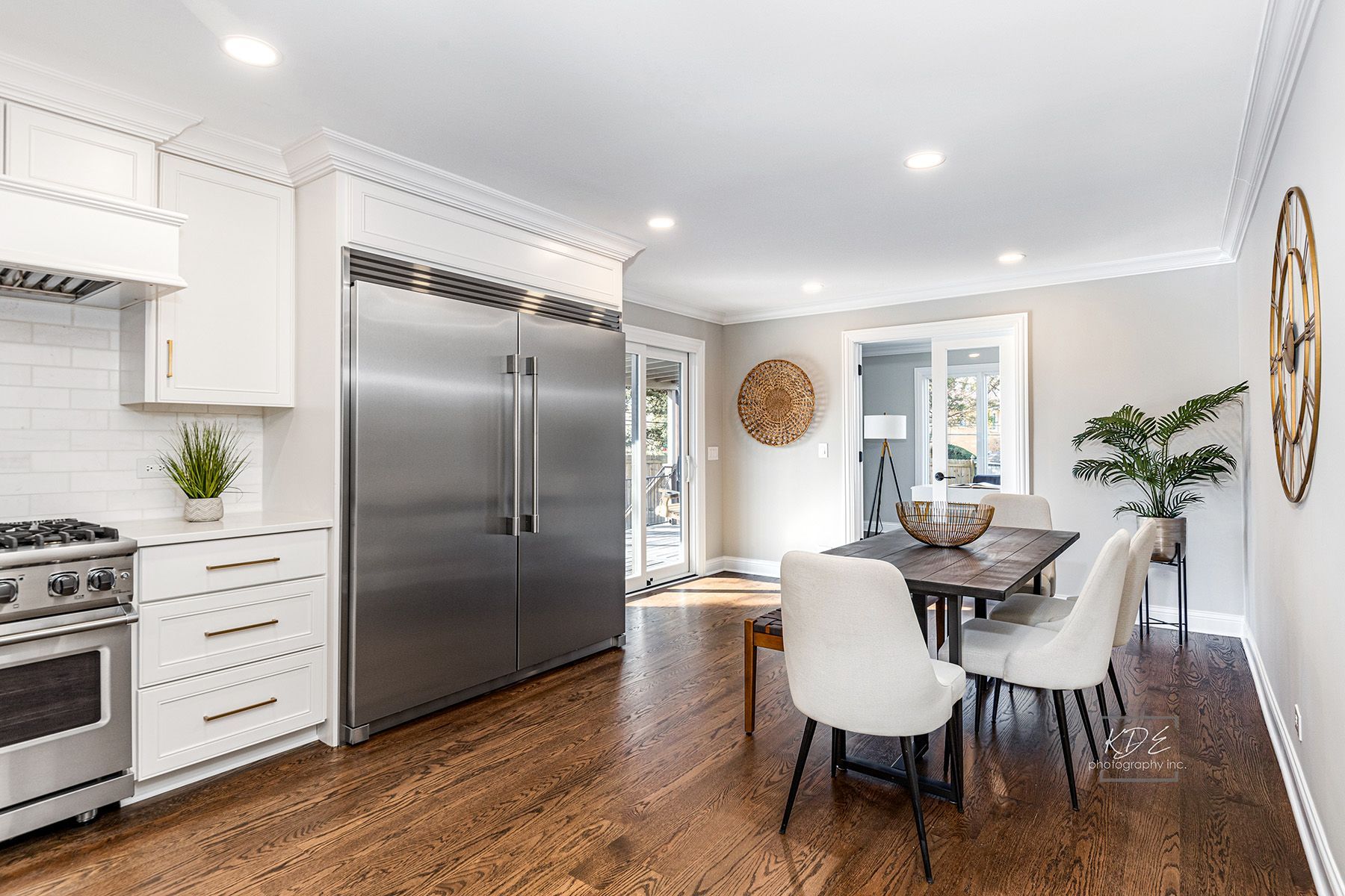A kitchen with stainless steel appliances , hardwood floors , a table and chairs.