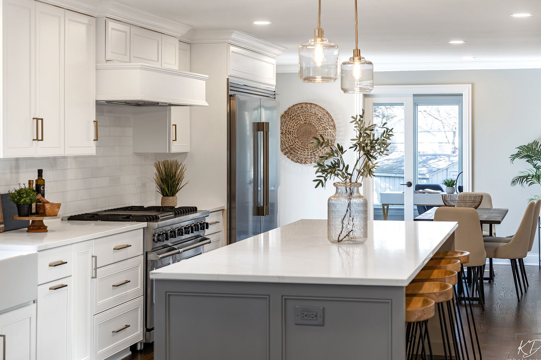 A kitchen with white cabinets , stainless steel appliances , and a large island.