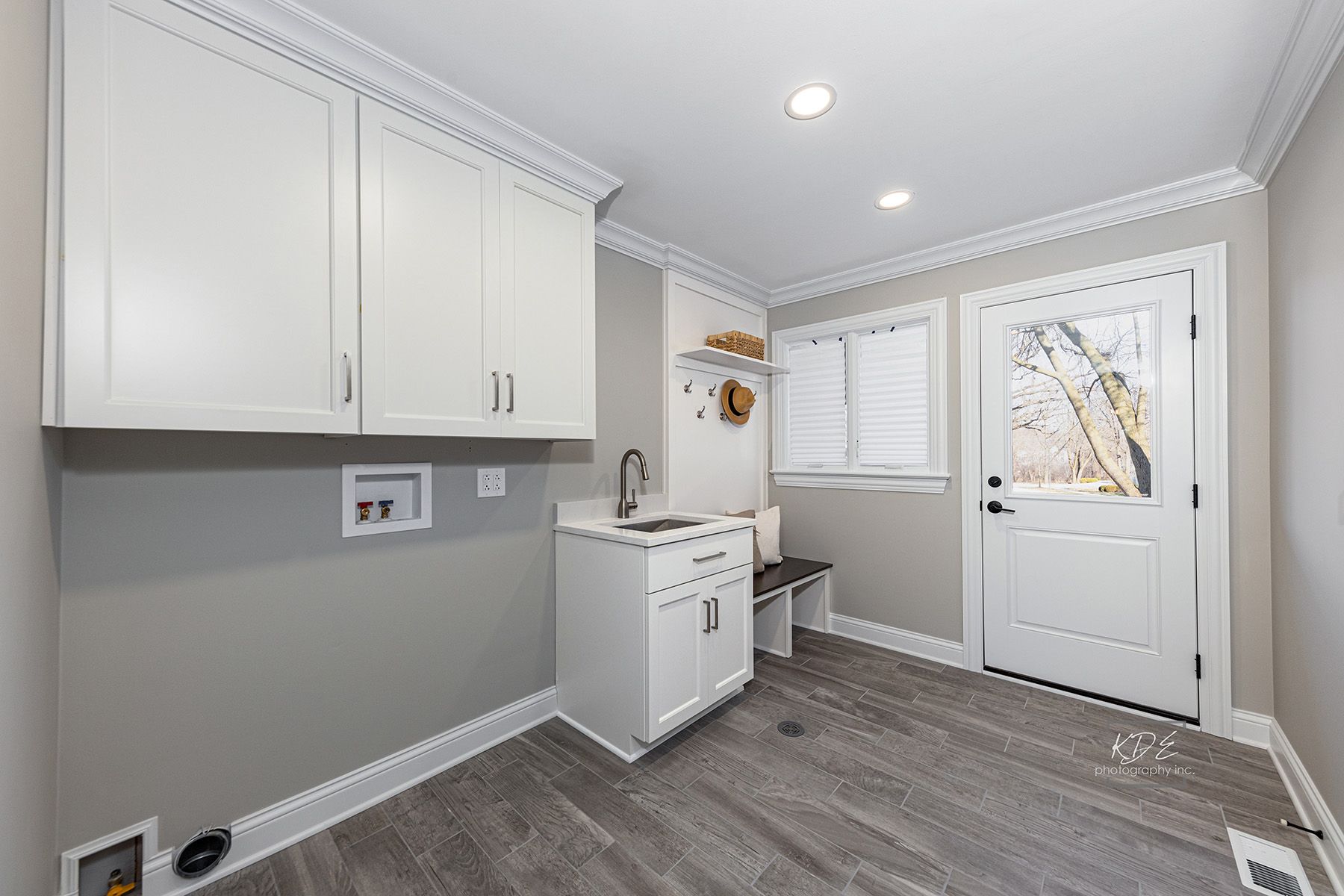 A laundry room with a sink , cabinets , and a door.