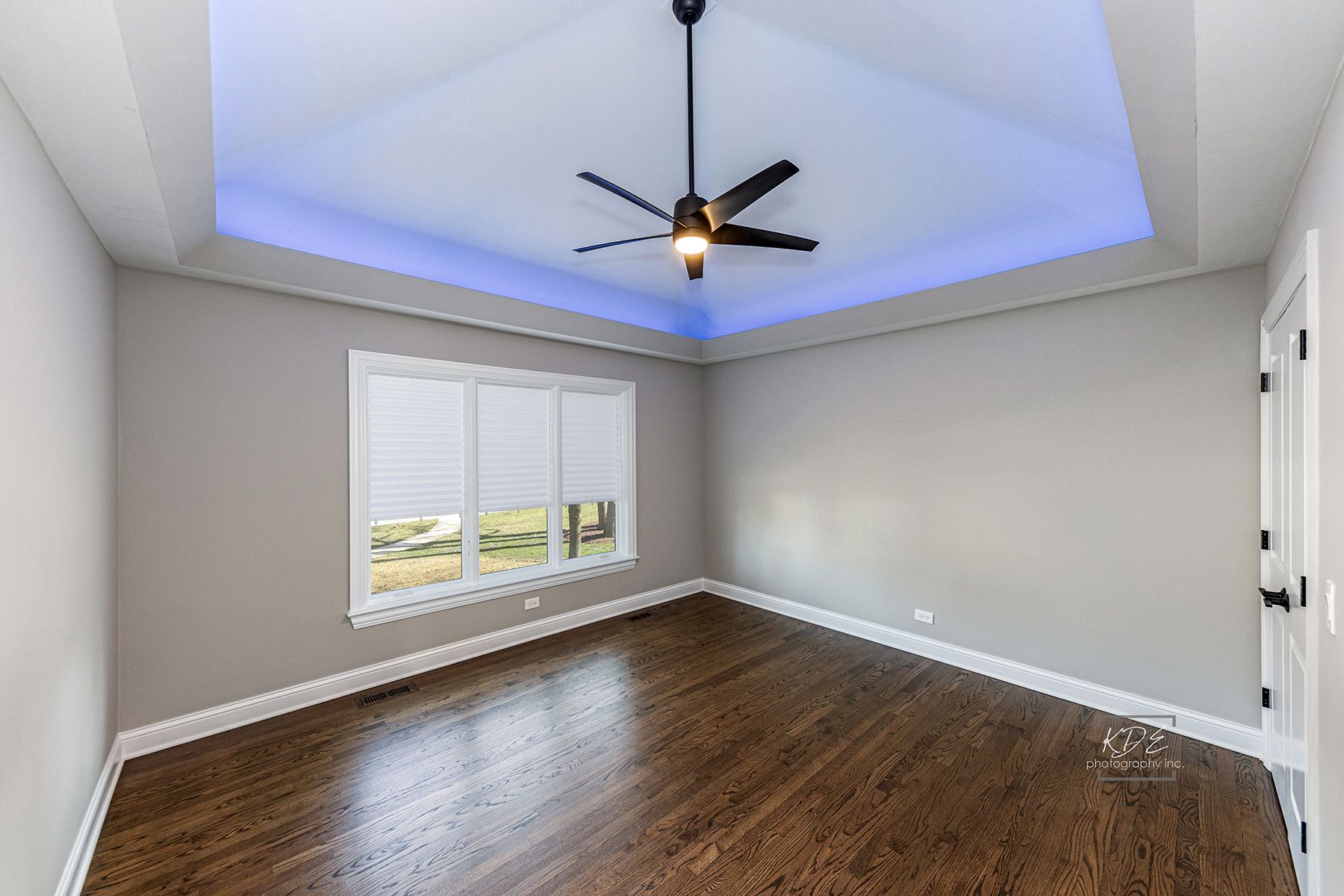 An empty room with hardwood floors and a ceiling fan.