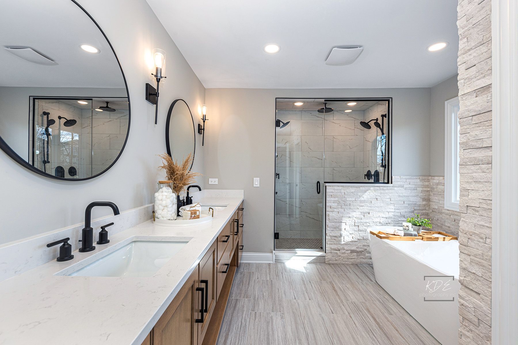 A bathroom with two sinks , two mirrors and a bathtub.