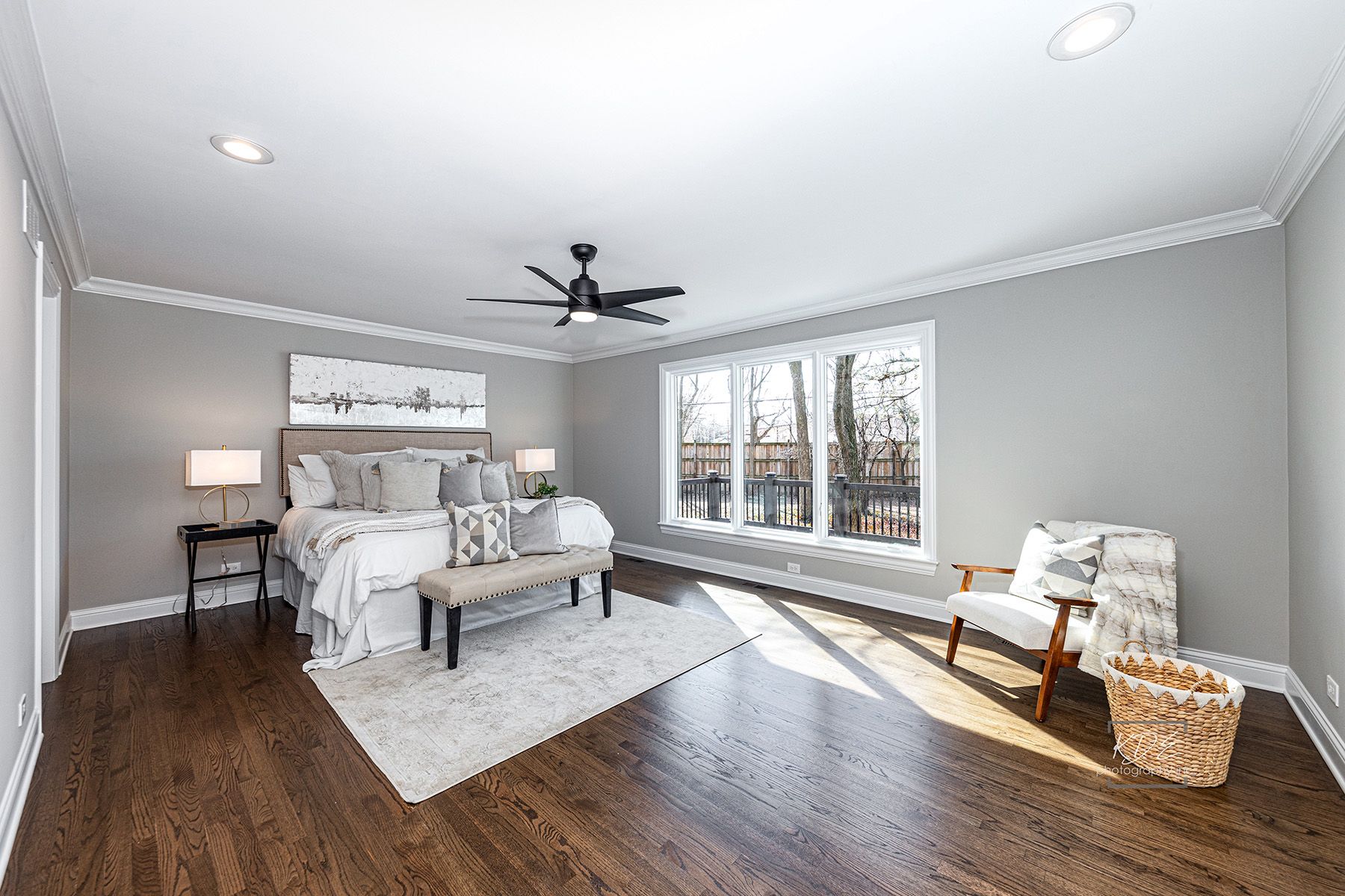 A bedroom with a bed , chair , bench and ceiling fan.