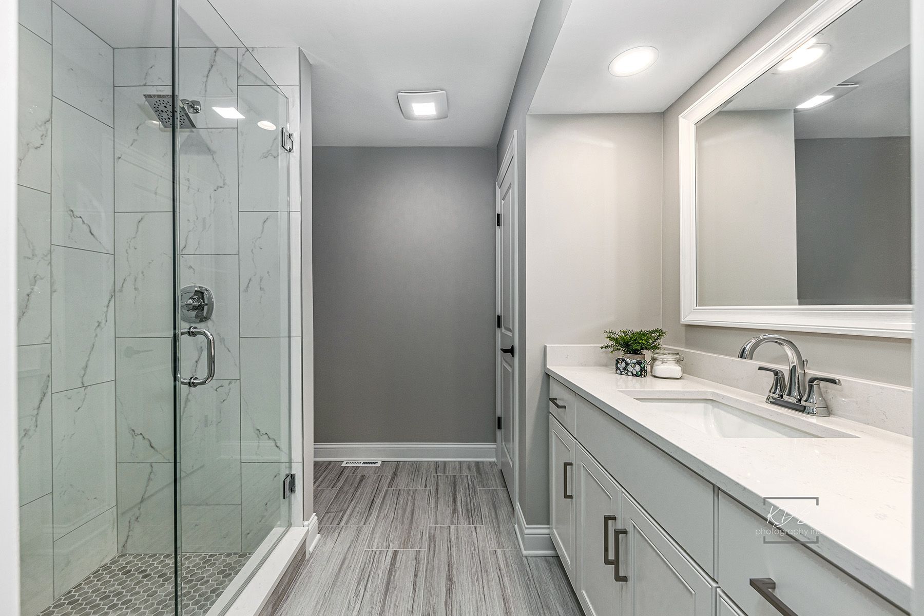 A bathroom with a walk in shower , sink and mirror.